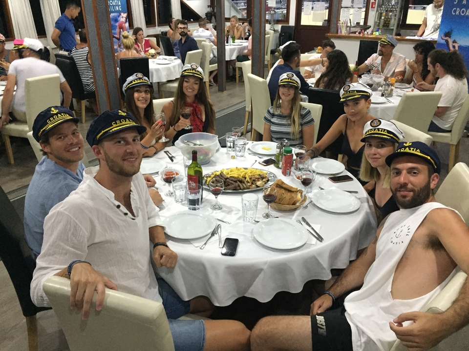 Un groupe de personnes dînant en portant des chapeaux de marin.