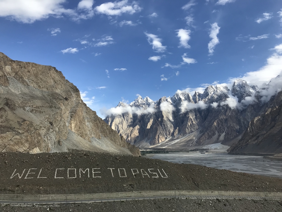 Paysage de montagne avec un panneau « BIENVENUE À PASU ».