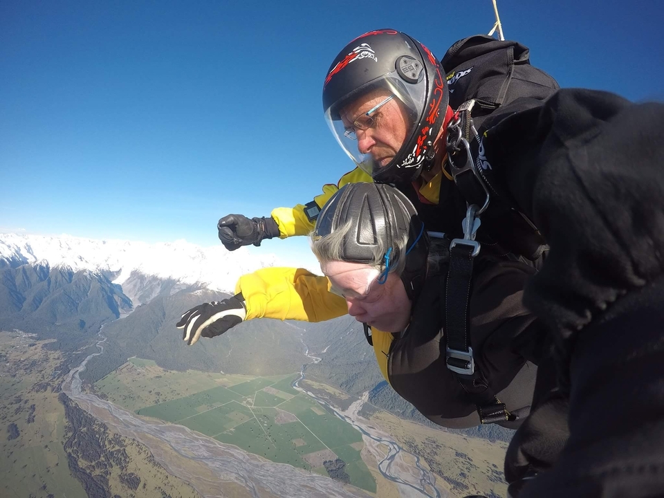 Parachutistes en chute libre au-dessus d'un terrain montagneux.