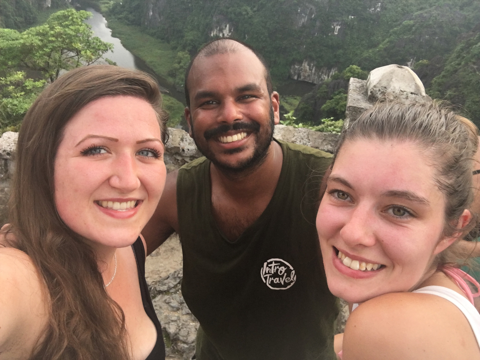 Trois amis souriants avec une vue sur des collines rocheuses.