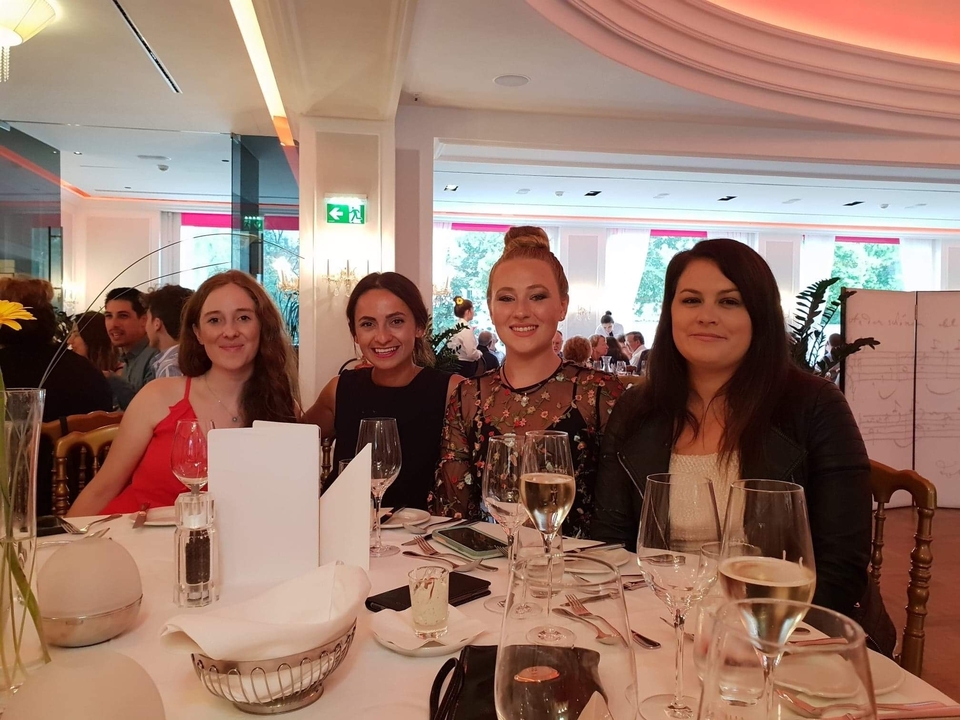 Groupe de femmes assises à une table à manger à l'intérieur.