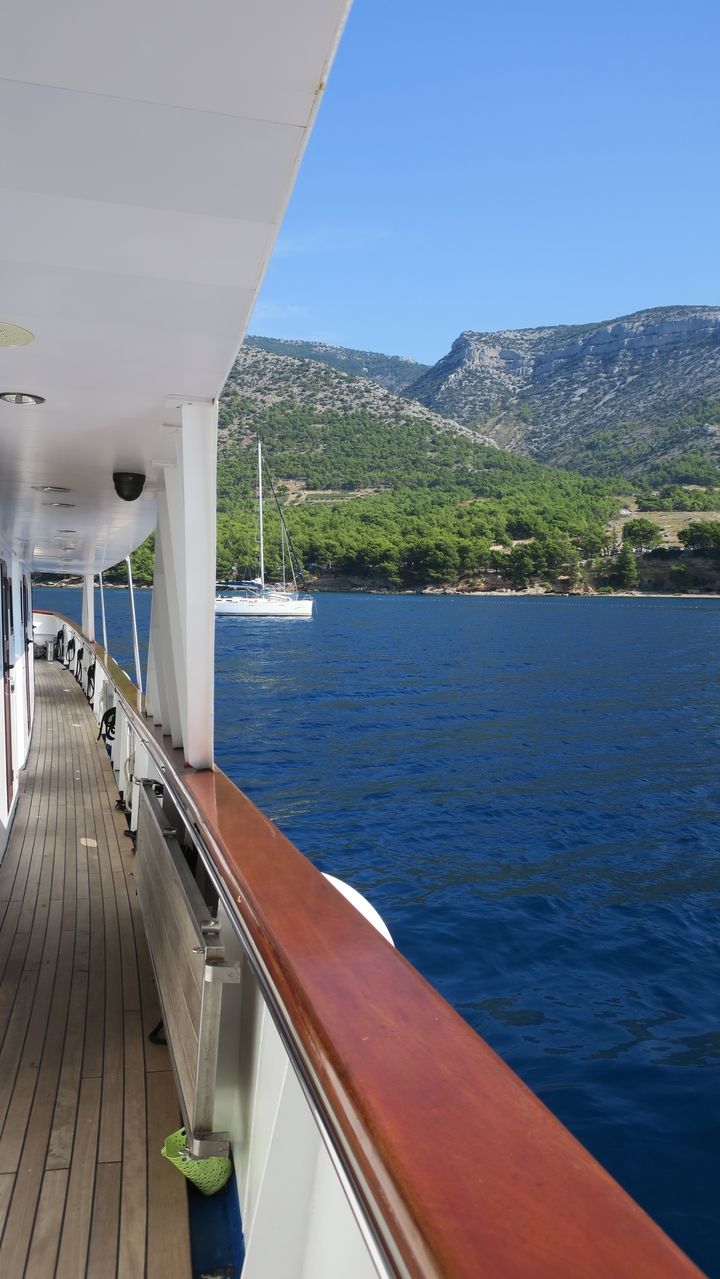Vue depuis un bastingage de bateau vers un yacht dans une baie.
