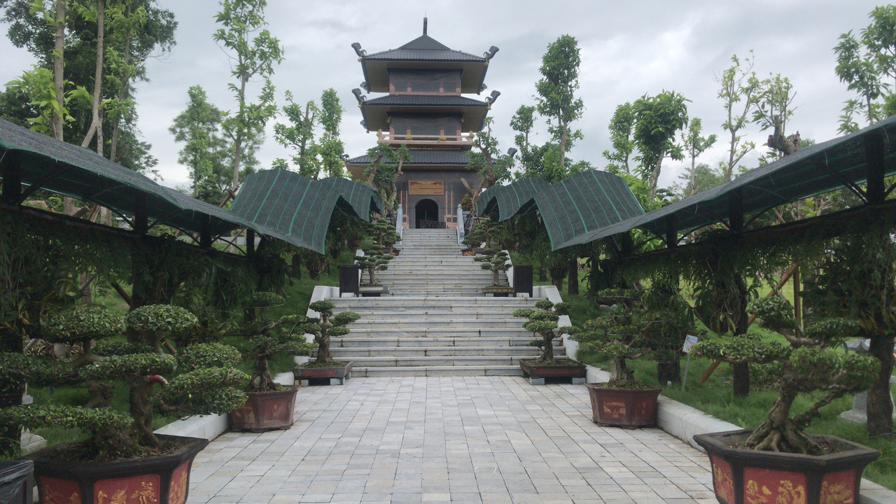 Entrance to a temple with steps and green topiary trees.