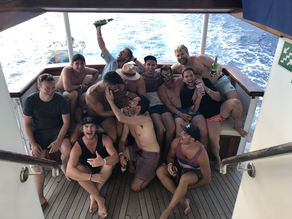 Groupe d'amis qui célèbrent et posent sur un bateau avec des bières.