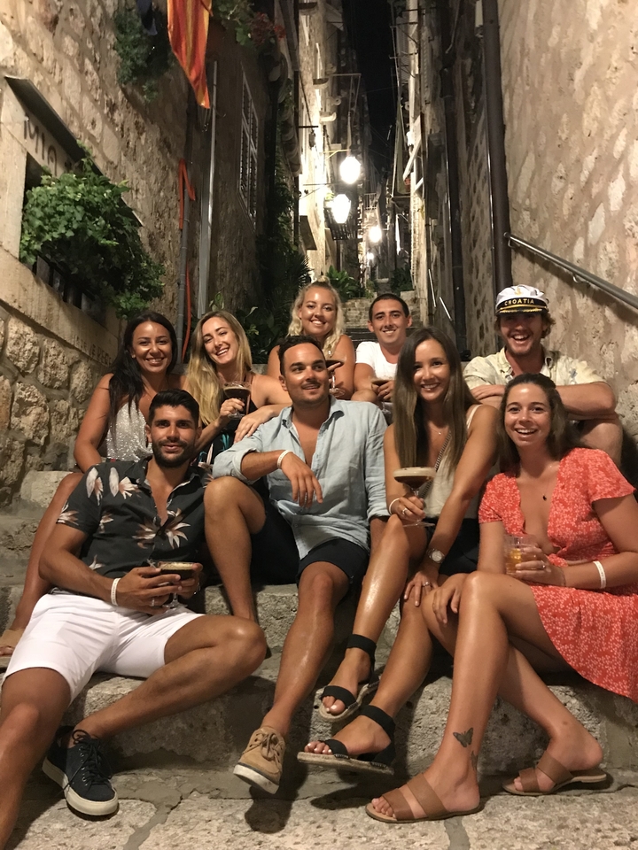 Groupe de personnes assises sur des marches dans un cadre de rue animé.