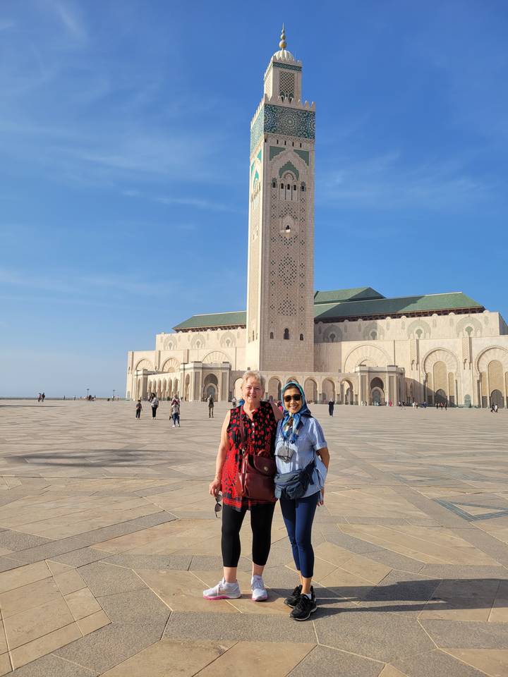 Two people posing in front of a tall mosque tower.