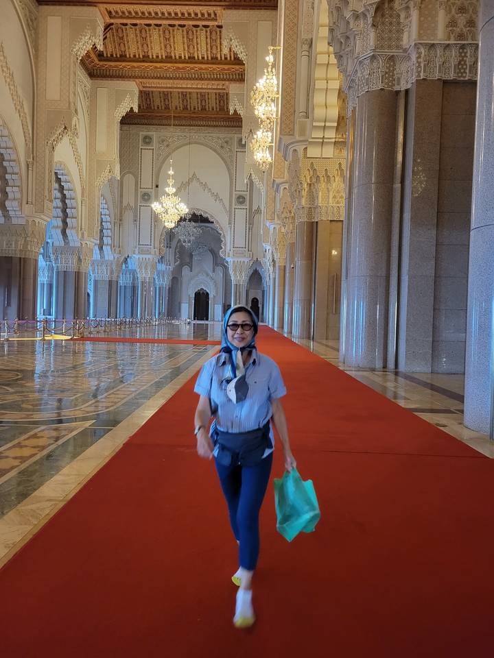 Person walking indoors through a spacious, elaborately decorated hall.