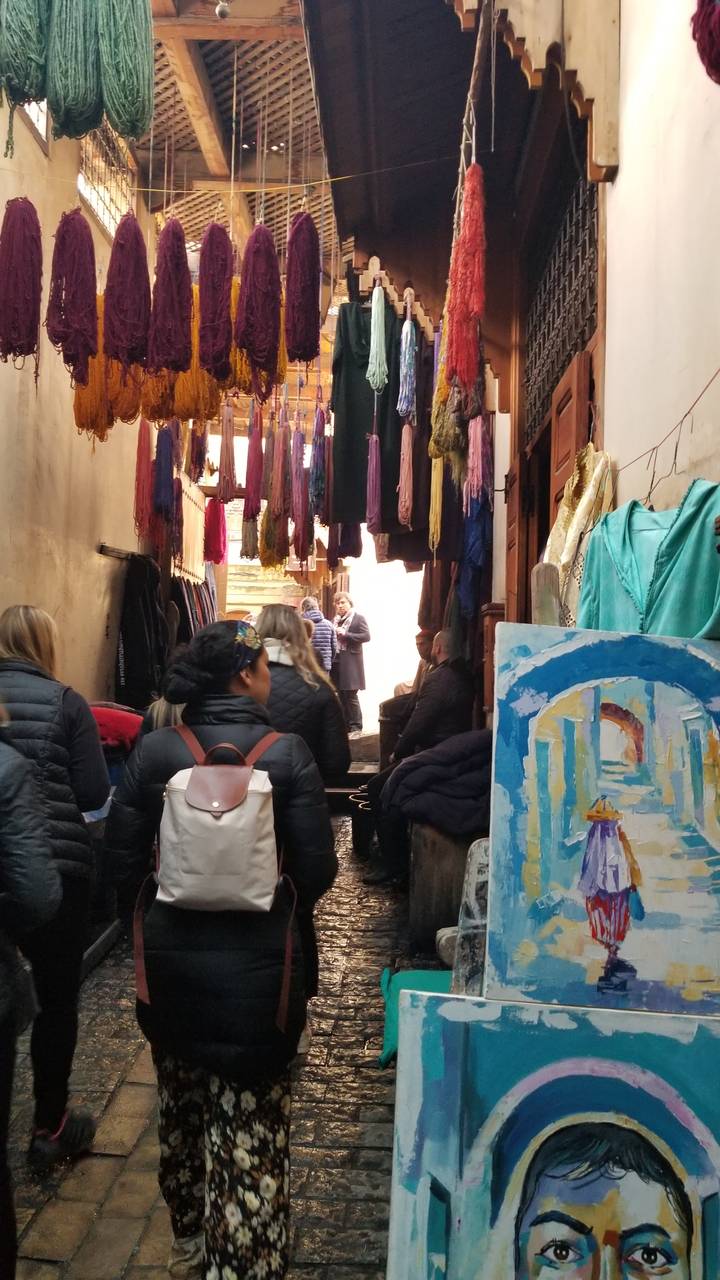 Markt mit hängenden Textilien und einer Kunstausstellung.