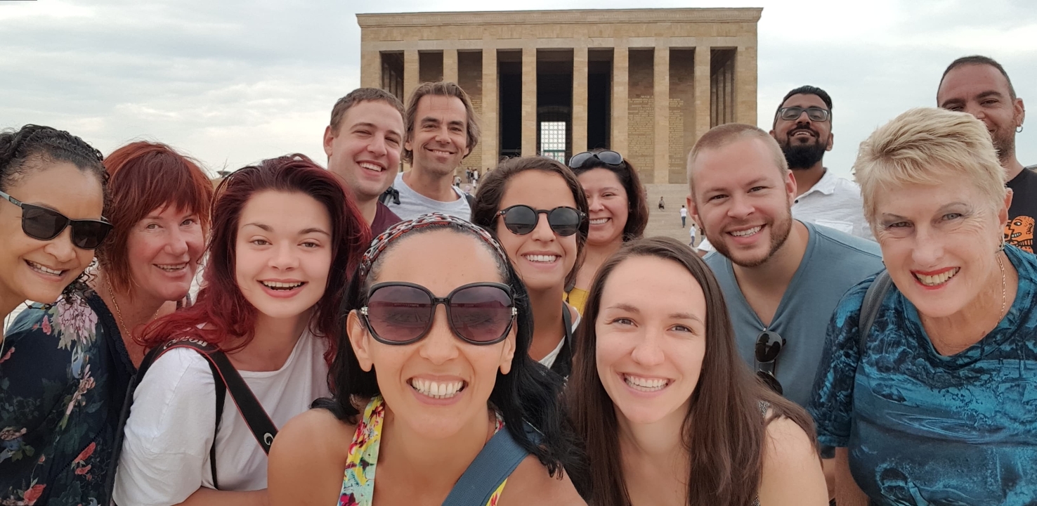 Selfie de groupe devant un grand bâtiment historique.