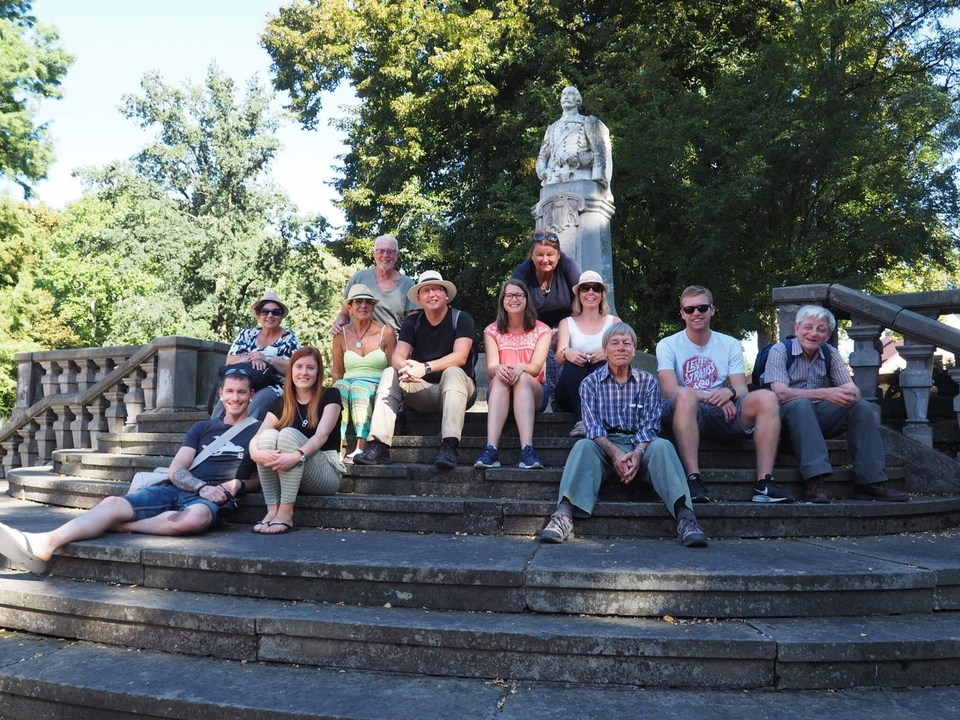 Groupe de personnes assises sur des marches devant une statue.