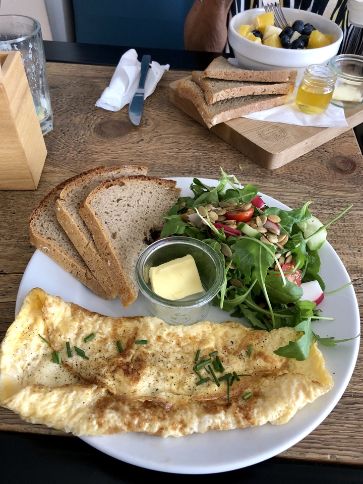 Assiette avec omelette, pain, salade et beurre.