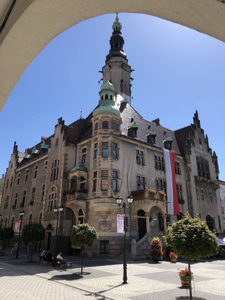 Bâtiment historique avec une tour d'horloge et des drapeaux devant.