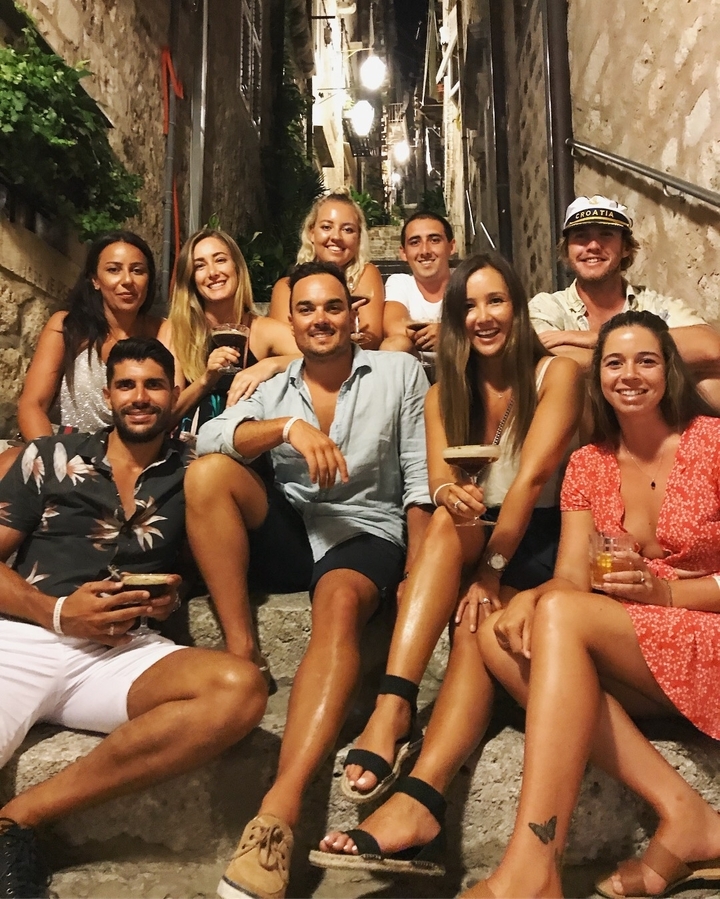 Groupe de personnes assises sur des marches, tenant des boissons.