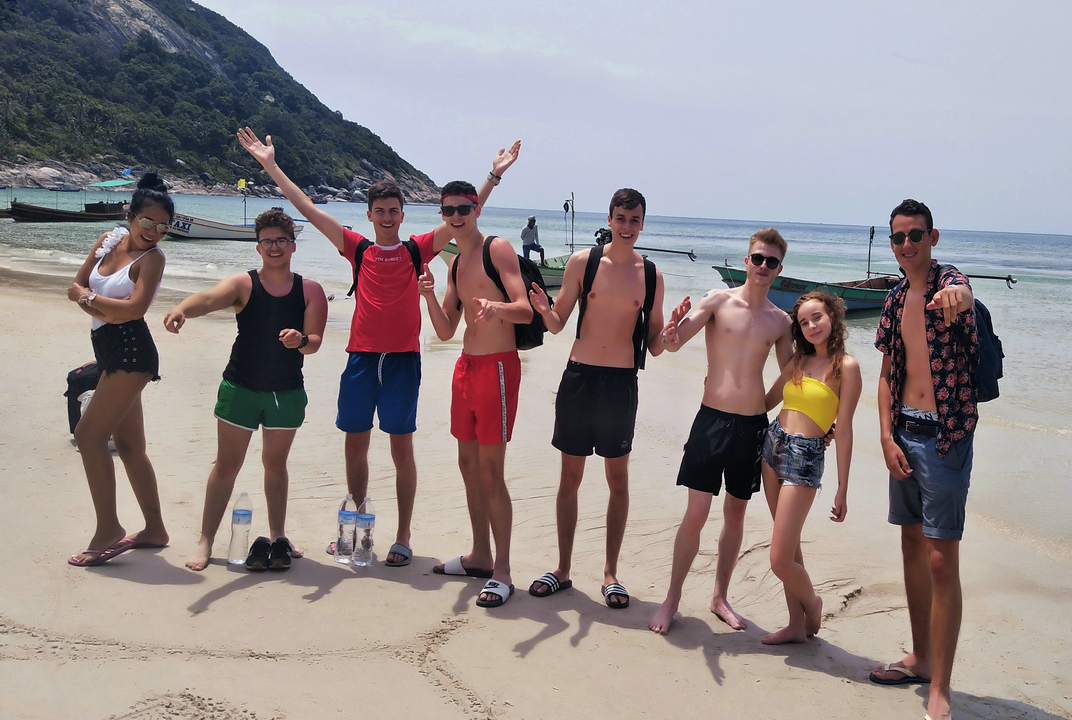 People smiling and posing on a beach.