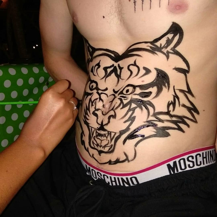 Person getting a tiger design painted on their chest.