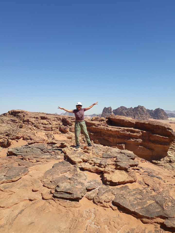 Personne debout sur un affleurement rocheux avec vue panoramique sur le désert.
