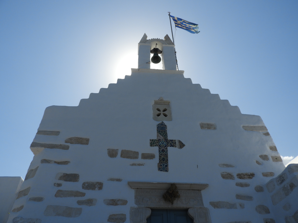 Église blanche avec un clocher contre le soleil.