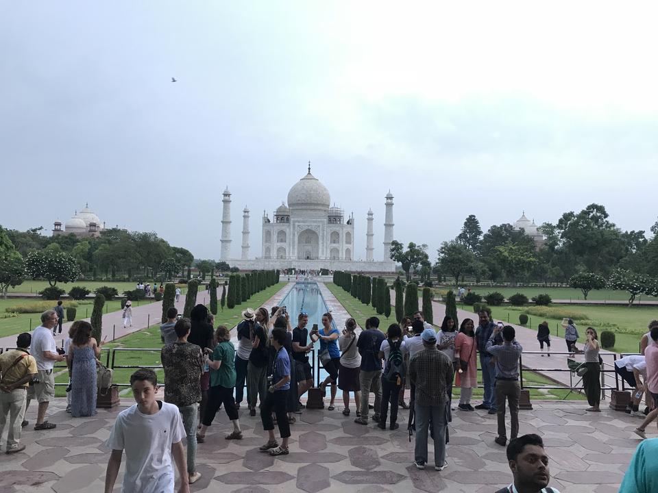 Des touristes au bassin de réflexion du Taj Mahal.
