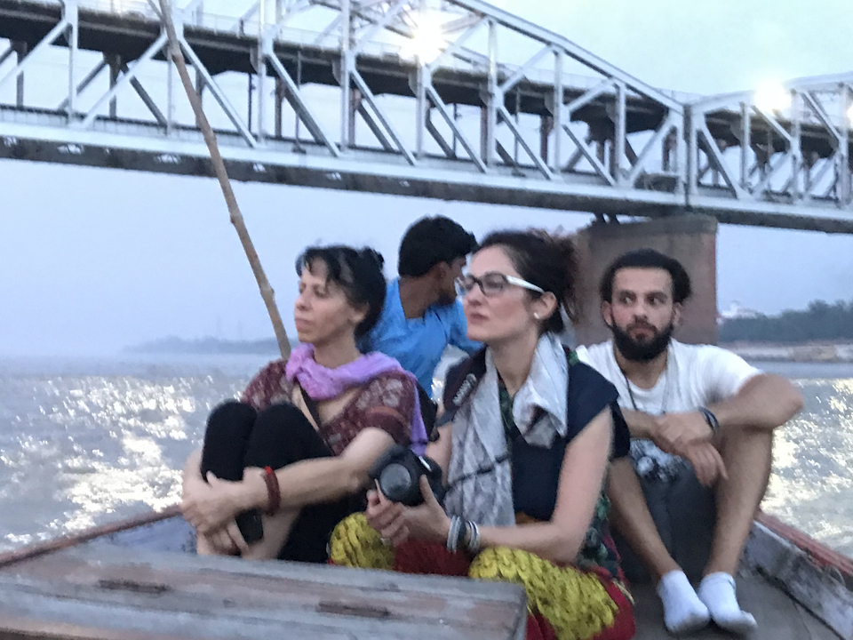 Des gens assis dans un bateau sous un pont au crépuscule.