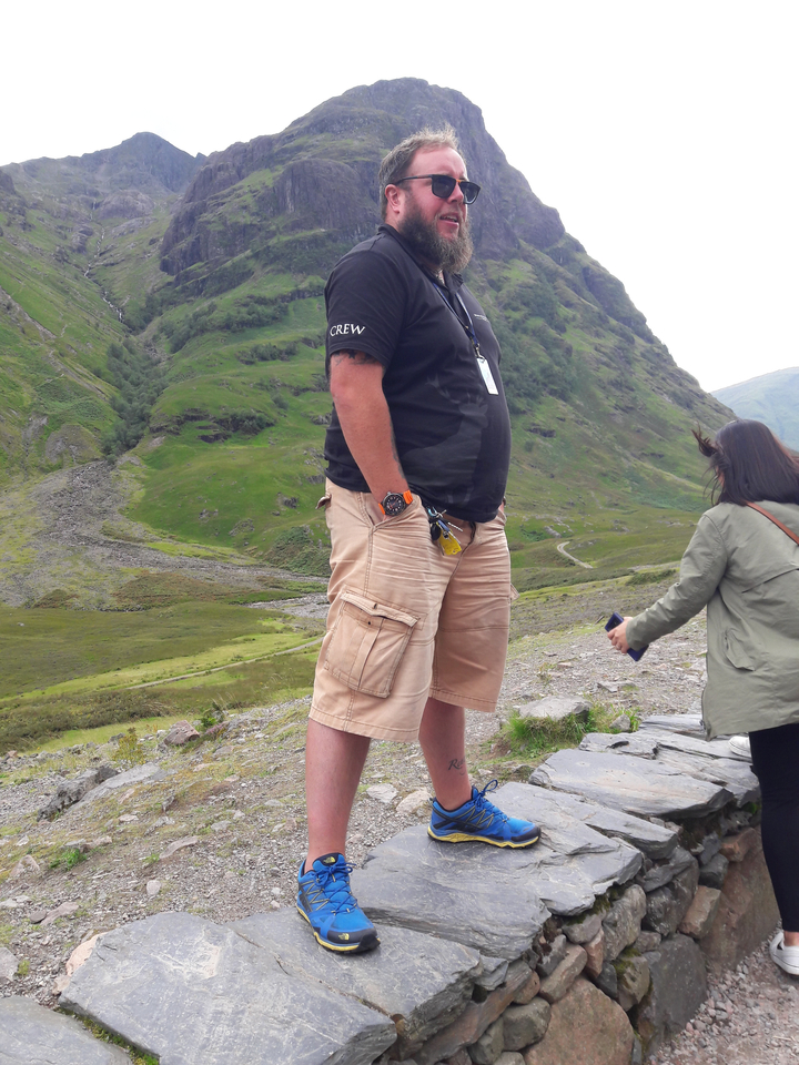 Deux personnes à l'extérieur avec des collines rocheuses en arrière-plan.