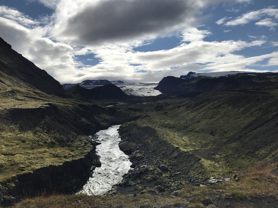 Rivière serpentant à travers une vallée profonde avec des sommets enneigés.