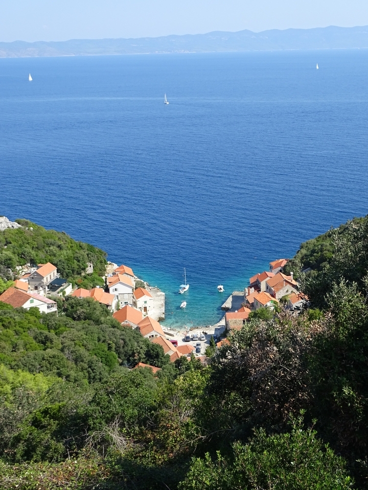 Village côtier coloré aux toits de tuiles rouges adjacent à une mer bleue limpide.