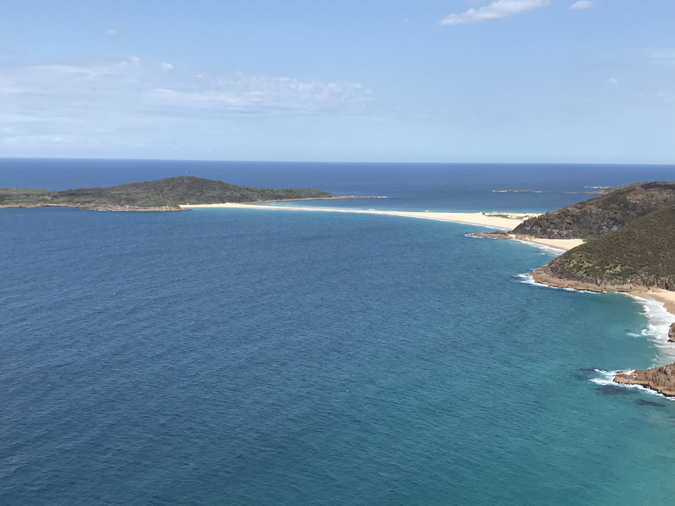 Expansive ocean view with distant sandy shores under a bright sky.