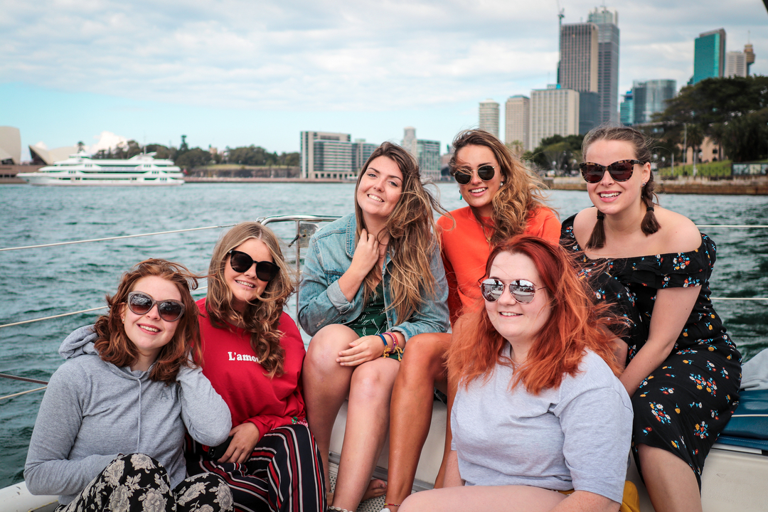 Group of friends on a boat with cityscape in the background.