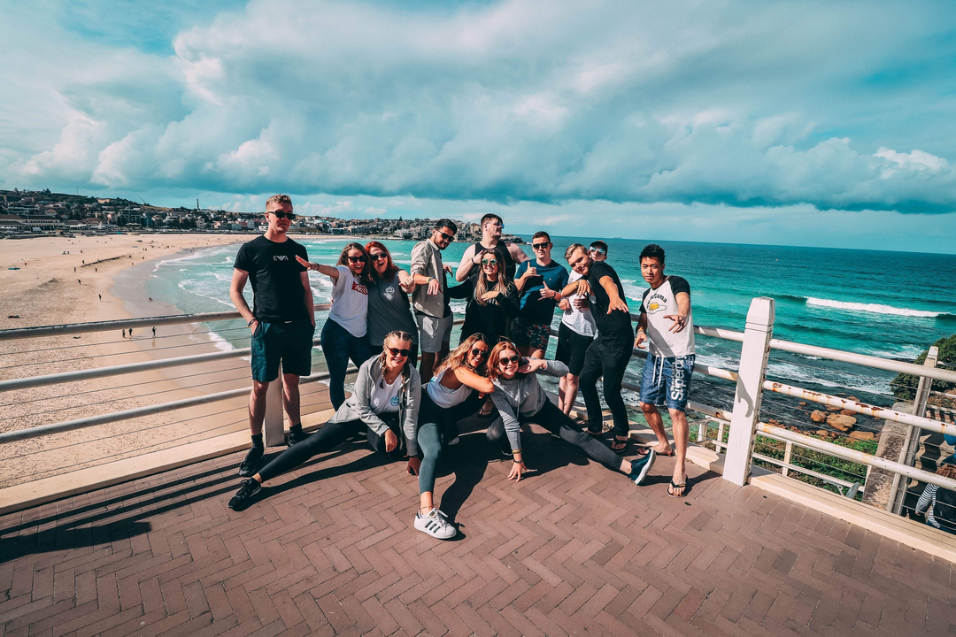 Group posing on a boardwalk with a beach and ocean backdrop.