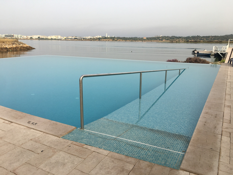Piscine à débordement avec vue sur un plan d'eau calme.