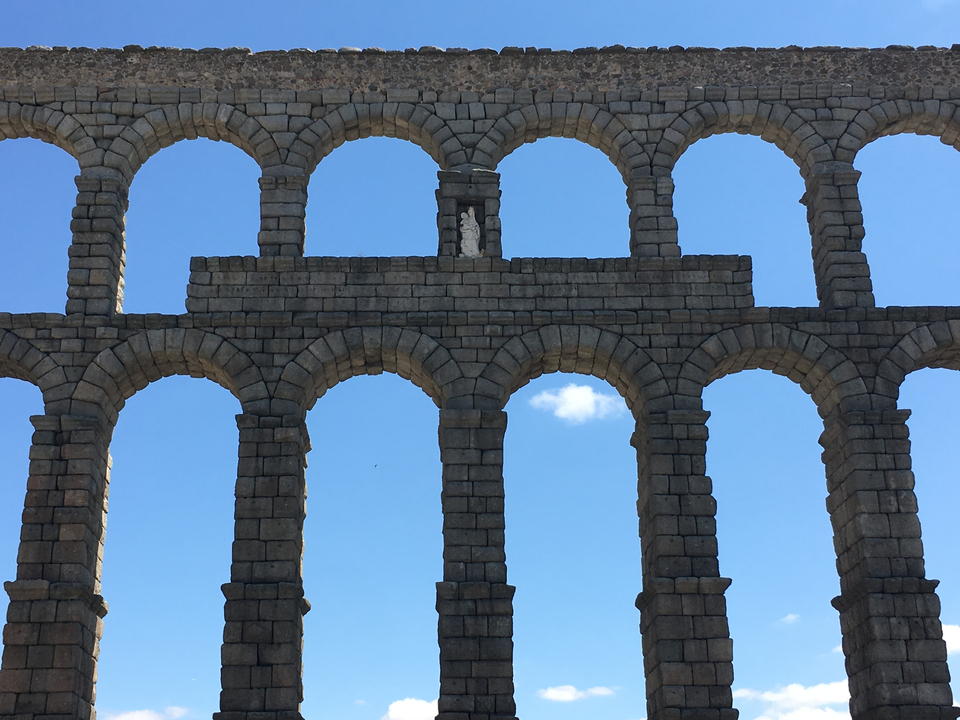 Arches de pierre anciennes contre un ciel bleu clair.