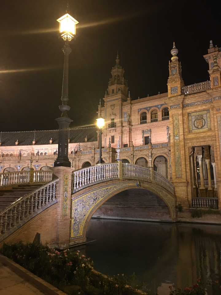 Bâtiment historique illuminé la nuit avec des arches décoratives.