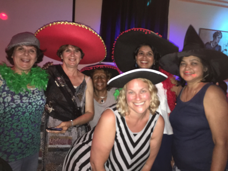 Groupe de femmes portant des chapeaux colorés posant ensemble.
