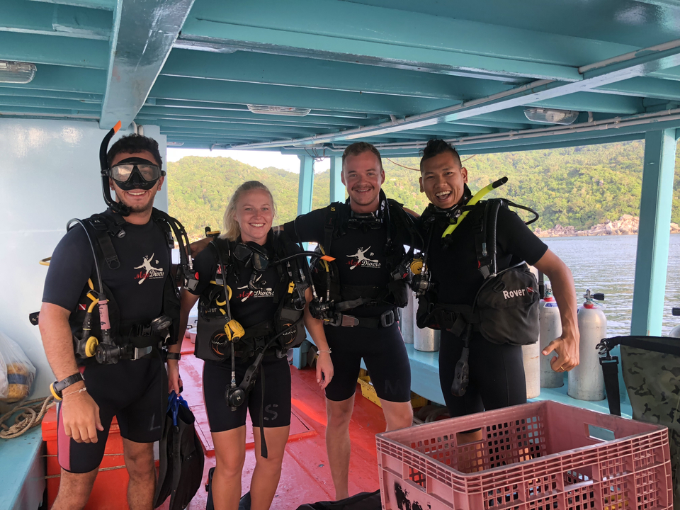 Group of divers posing on a boat.