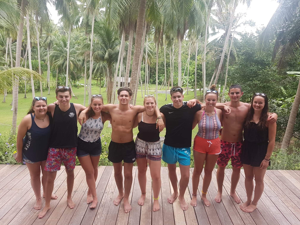 Group of friends posing in a tropical setting with palm trees.