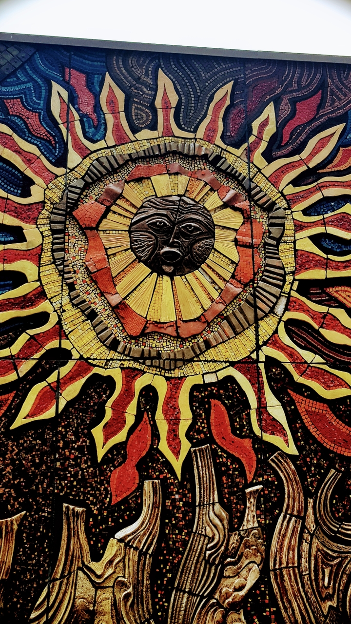 Œuvre d'art en mosaïque représentant un soleil avec un visage.