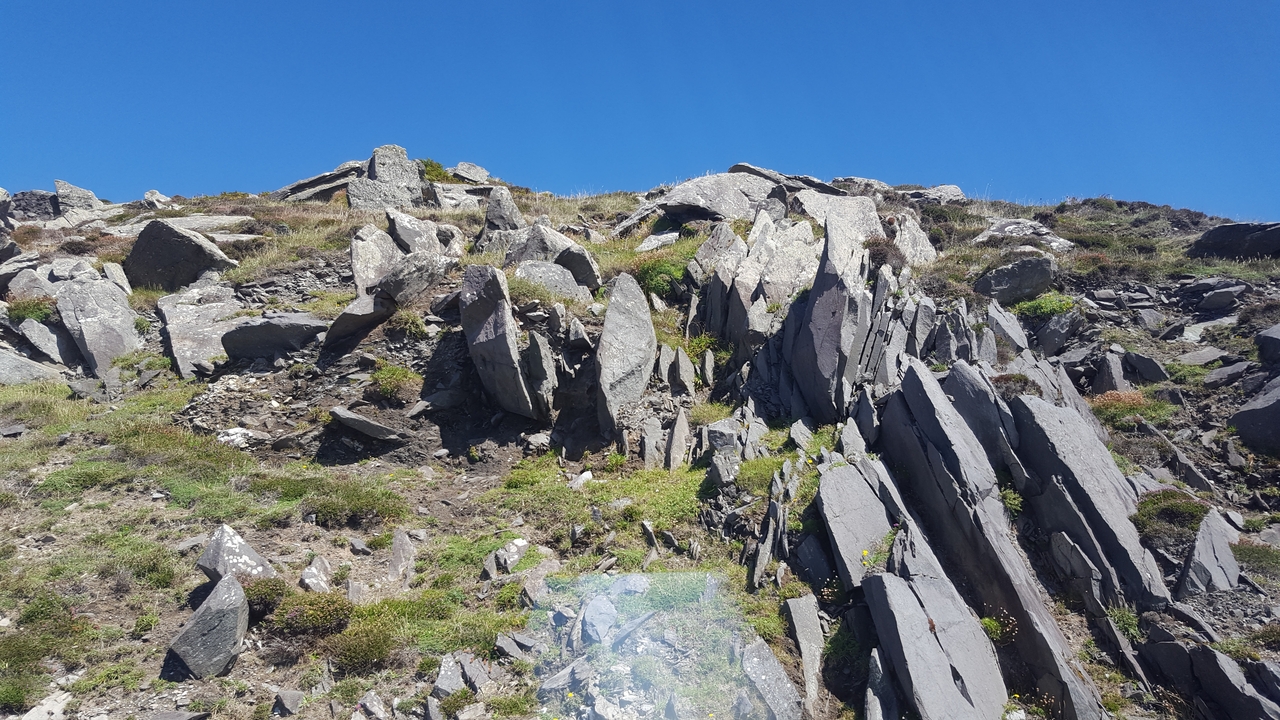 Rochers escarpés au sommet d'une colline sous un ciel bleu dégagé.