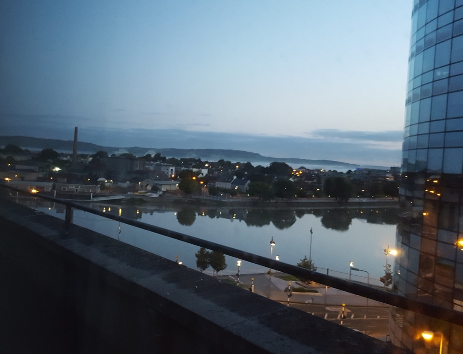 Vue d'une rivière et d'une ville au crépuscule depuis un balcon.