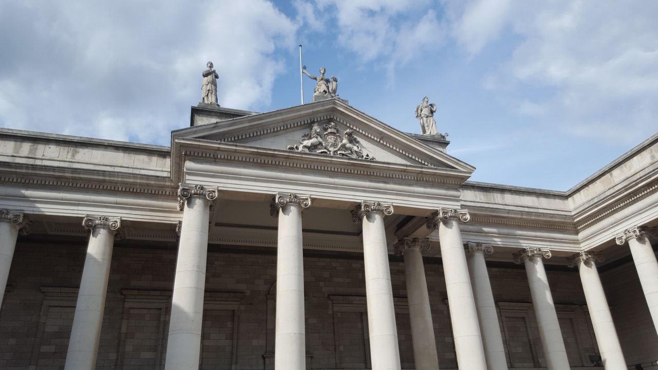Bâtiment architectural classique avec colonnes et statues.