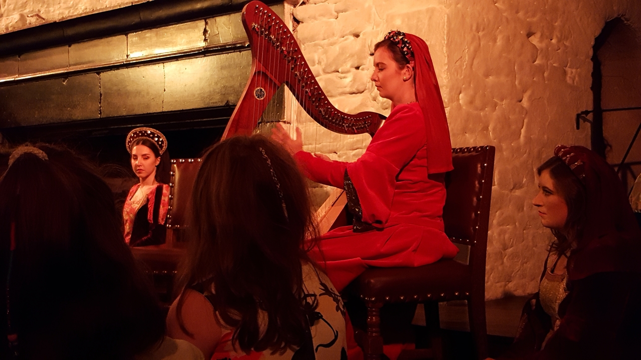 Artistes traditionnels jouant de la harpe en costumes rouges.