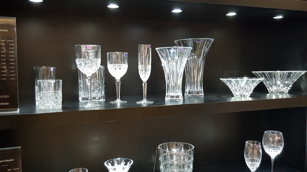 Exposition de verres en cristal et de vases sur une étagère.