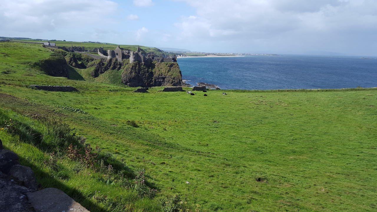 Ruines d'un château perché sur une falaise herbeuse au bord de la mer.