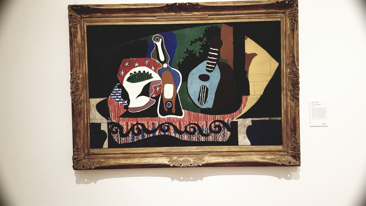 Peinture abstraite dans un cadre doré sur un mur de galerie.