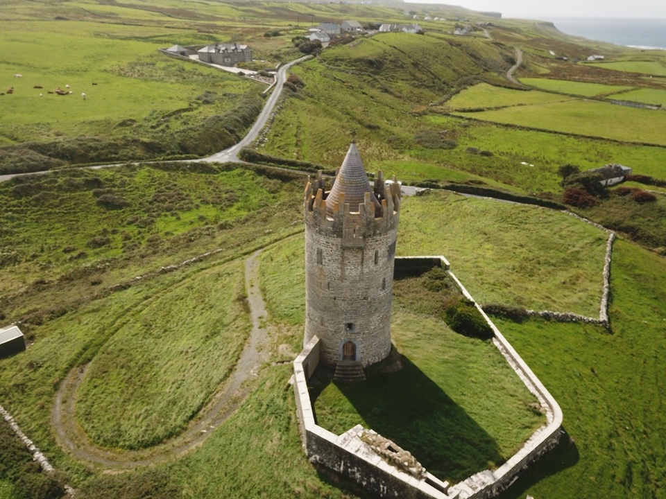 Tour de pierre située dans une campagne vallonnée et verdoyante.