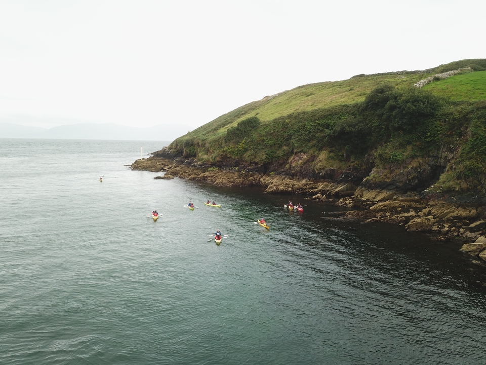 Des kayakistes explorent un littoral rocheux.