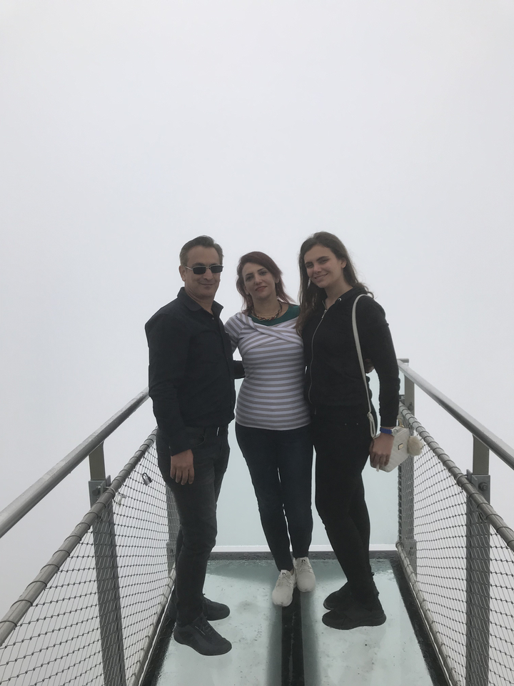 Trois personnes debout sur un belvédère brumeux.