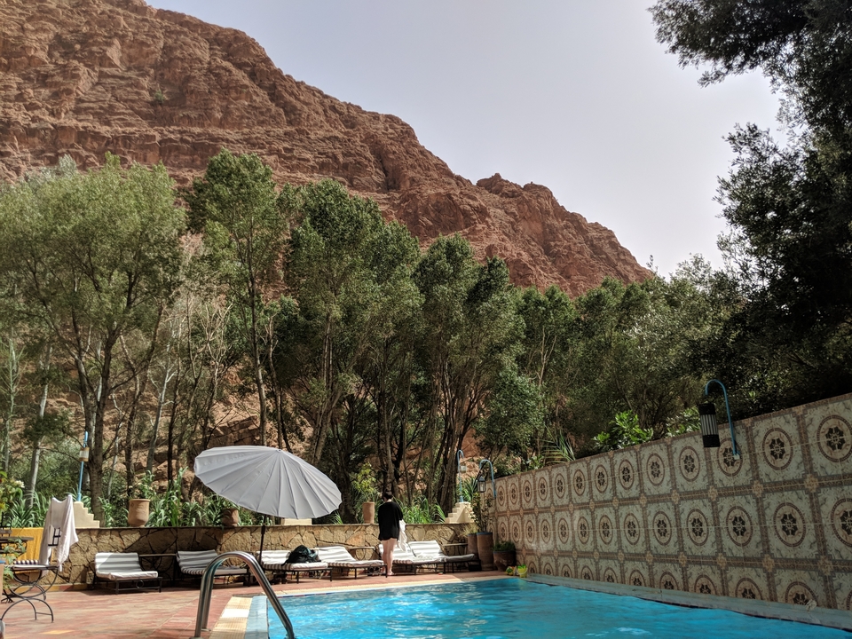 Vue panoramique d'un jardin avec un arrière-plan montagneux et des invités de jour.