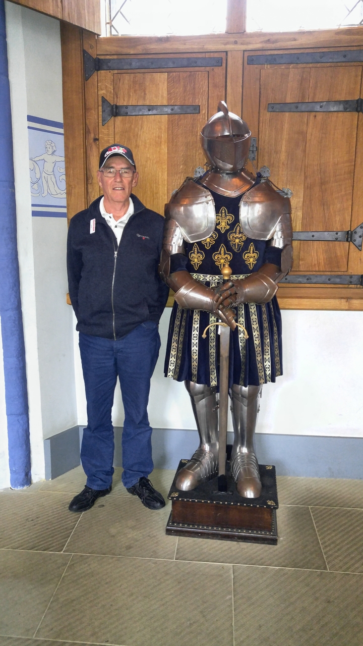 Une personne debout à côté d'une exposition d'armure de chevalier.