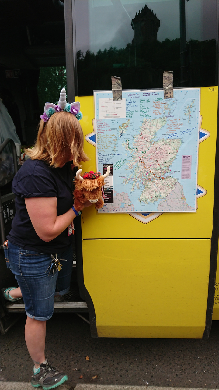 Personne tenant un animal en peluche à côté d'une carte de l'Écosse.