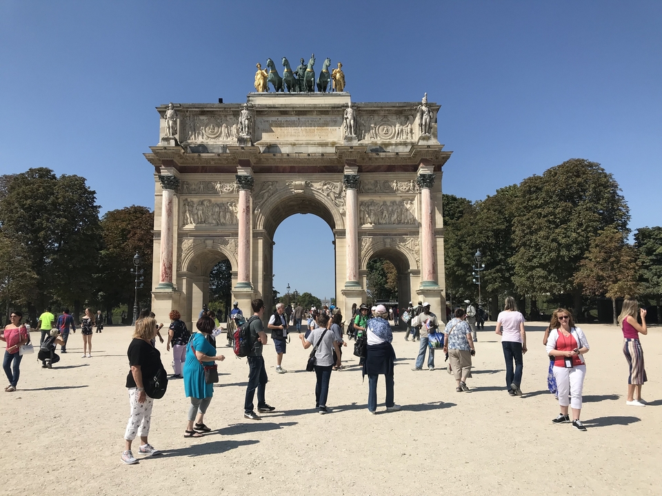 Des touristes se sont rassemblés près d'un monument en forme d'arc historique.